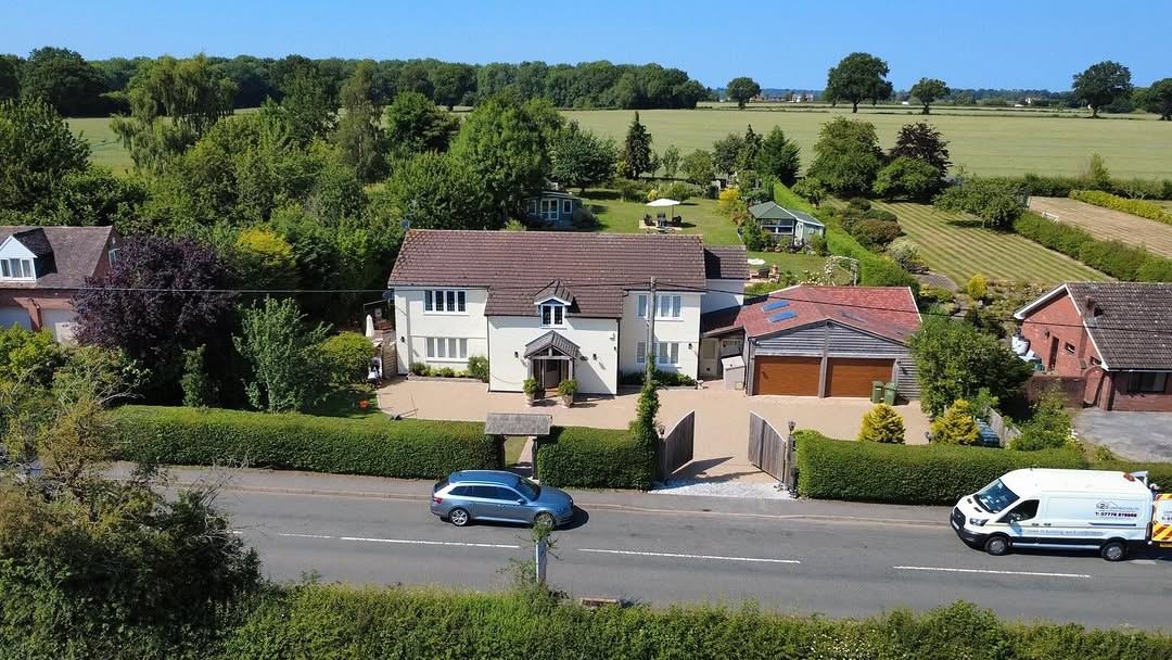 Aerial view of a white cottage with a new resin driveway, surrounded by countryside