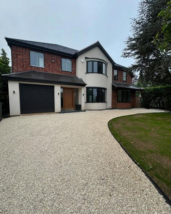 Curving gravel driveway with lawn in front of a modern house