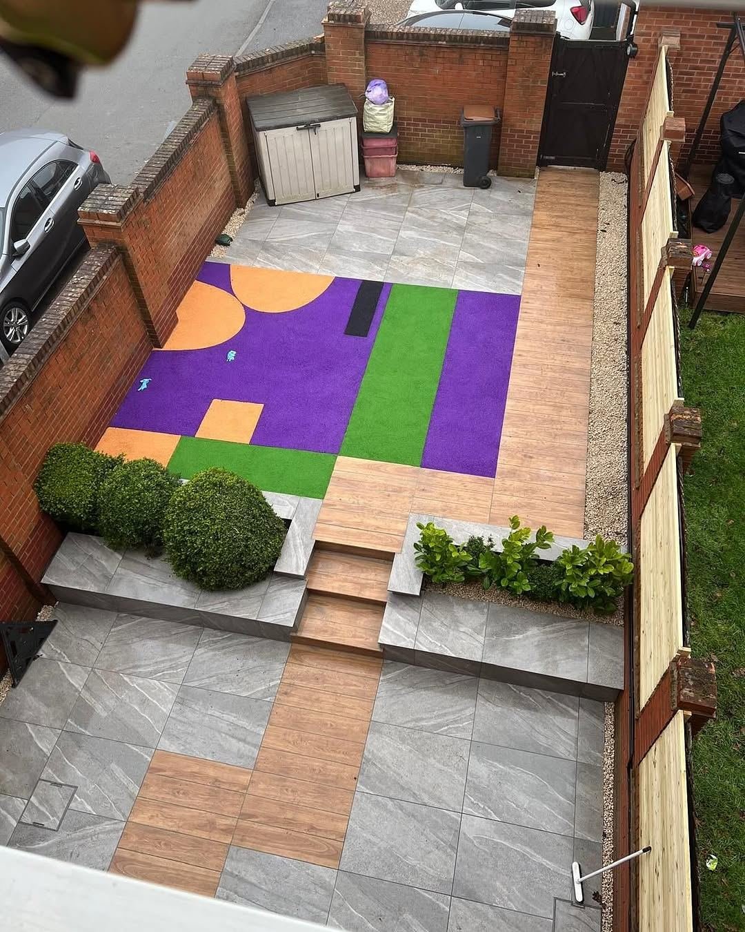 A garden with a colourful play surface in purple, green and orange shapes