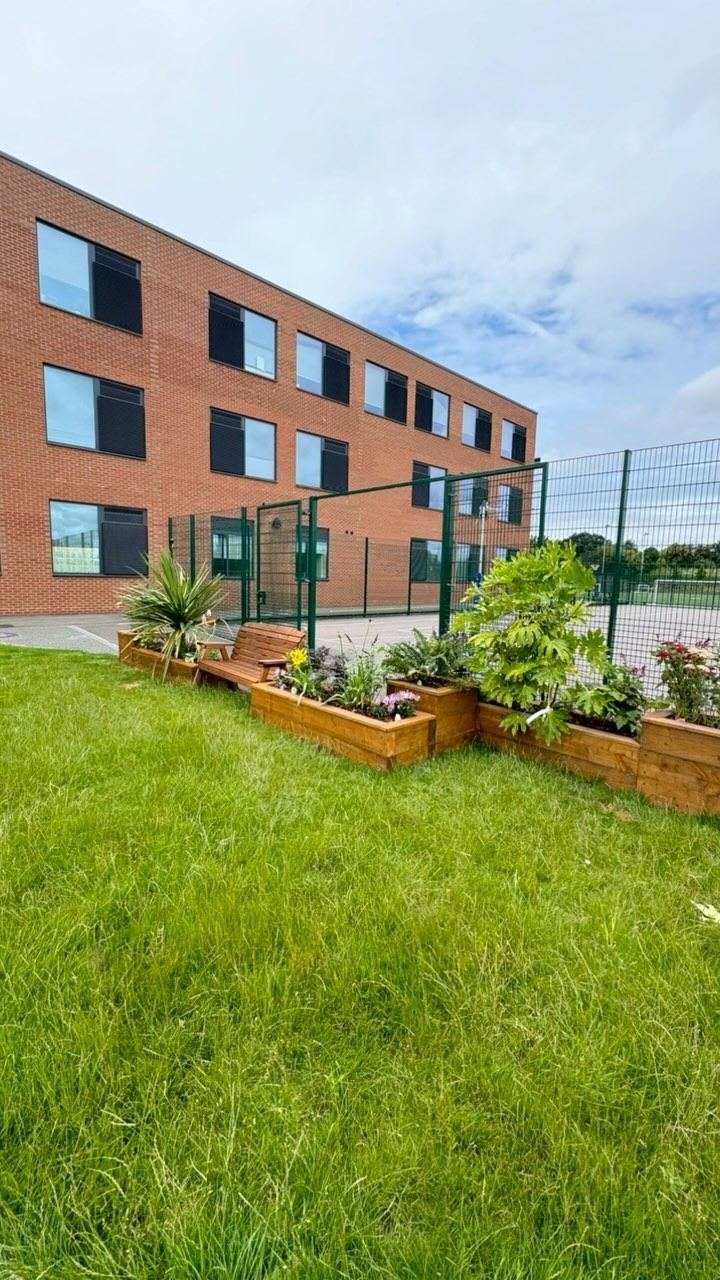 Timber raised planters filled with plants beside a modern brick building